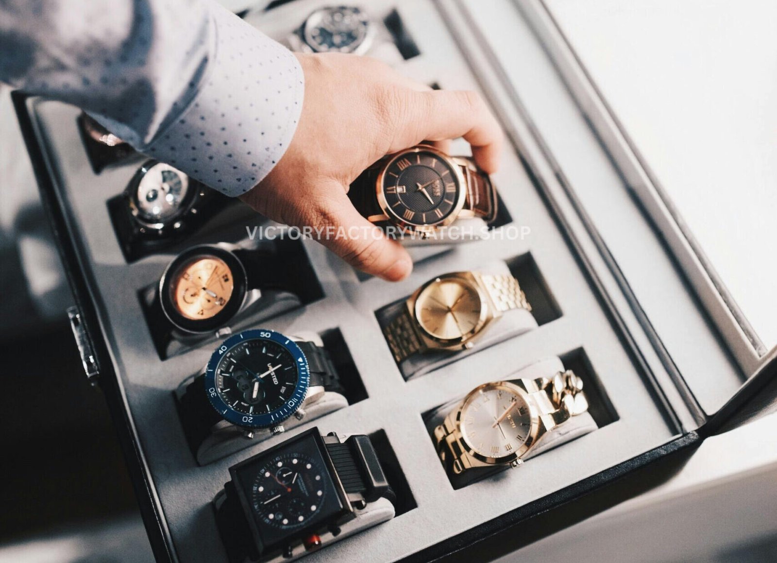 Luxury replica watches displayed in a premium watch case with a hand selecting a black dial timepiece, showcasing high-quality craftsmanship and variety