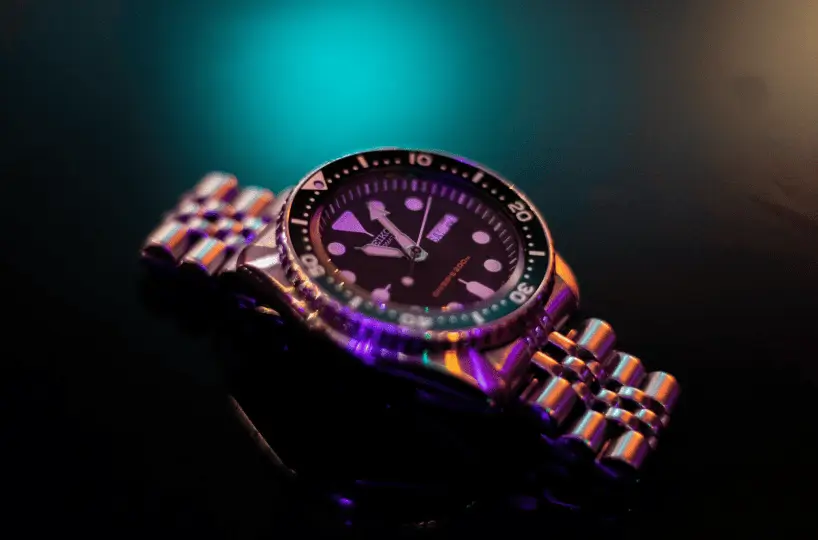 Close-up macro shot of a luxury chronograph dial with a navy blue face, silver hands, and subdials.