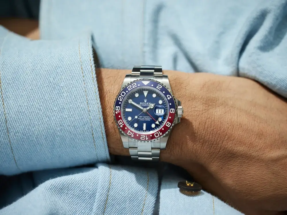 Rolex GMT-Master II Pepsi replica with blue and red bezel worn on wrist with denim shirt